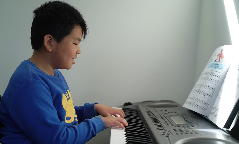 photo of boy playing keyboard